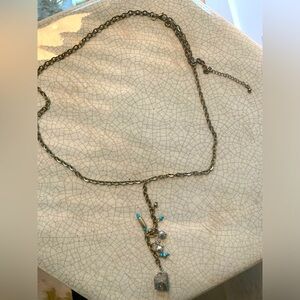 Golden long necklace with charms and golden stone at the end